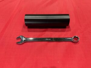 Snap-onスパナとの比較でサイズ感が分かる黒色アルマイト部品。精度と仕上げの美しさが際立つ。