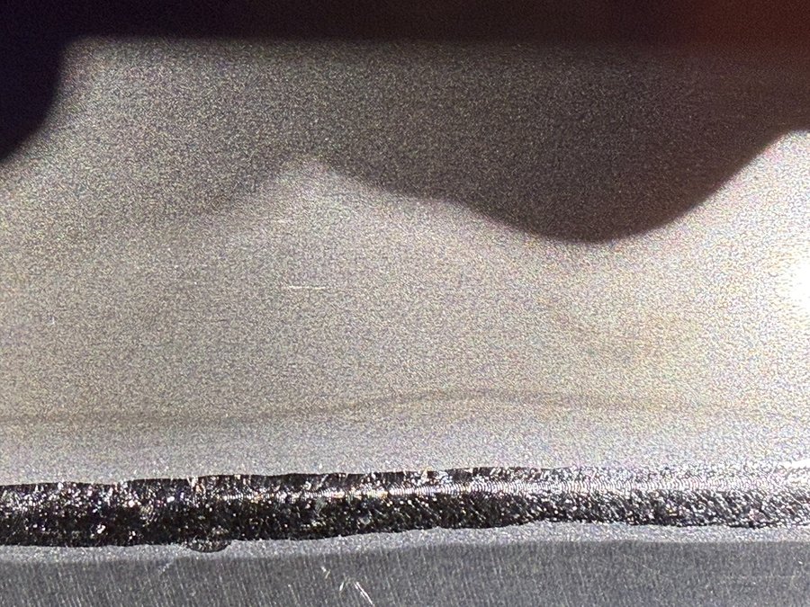 板金部材の端部に形成された溶接ビードの拡大写真です。ビード幅・余盛・表面の凹凸を確認し、アンダーカットやピットの有無など外観品質の検査・工程記録・管理に役立ちます。