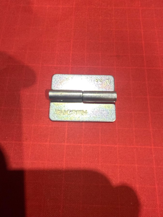 亜鉛メッキ蝶番(剥離前)の外観写真。溶接線に亜鉛が残るとTIG入熱で蒸発して爆ぜやすく、スパッタ増・ピット・電極汚染の原因になります。作業前に裏表で完全剥離が必要です。